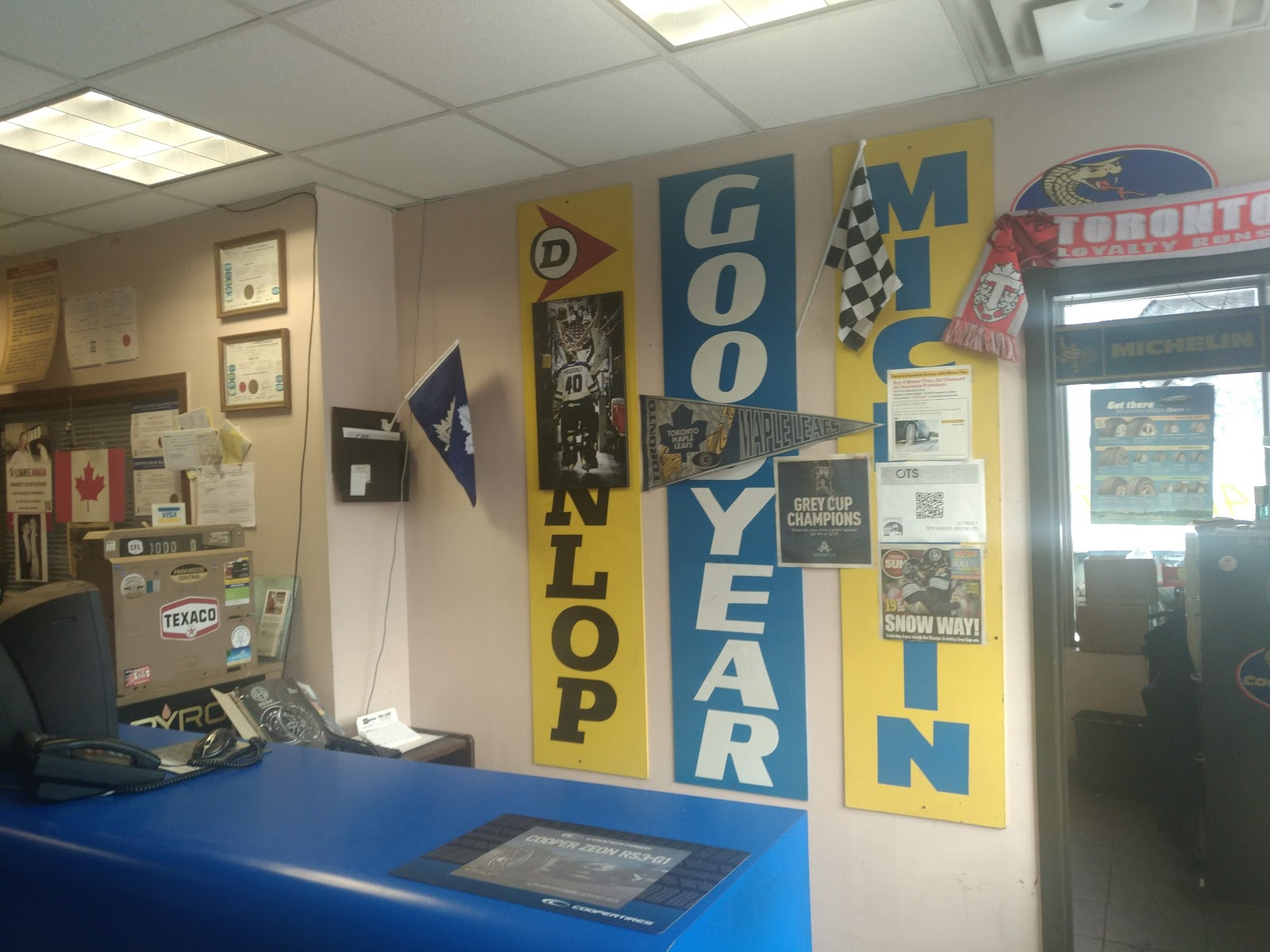 Dunlop, Goodyear, and Michelin brand banners behind the counter